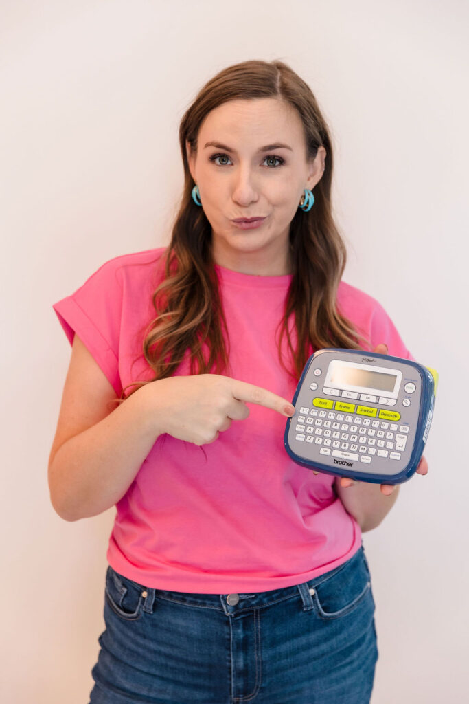 Woman holding label maker and pointing to it
